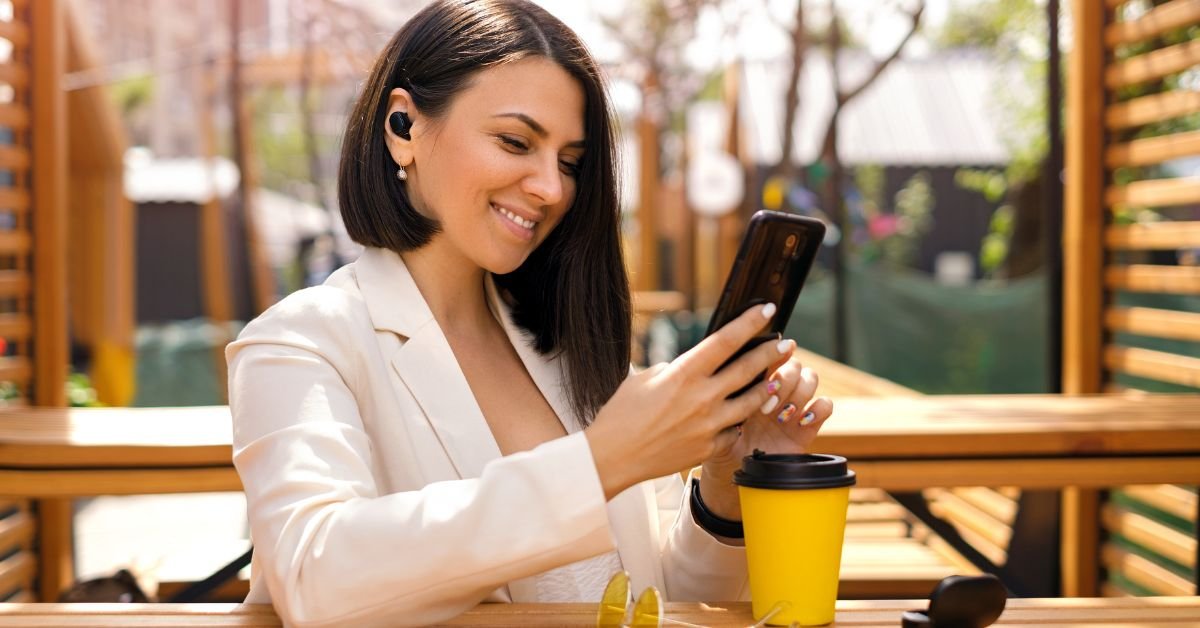 woman listening to muisc with noise-cancelling earbuds in a cafe