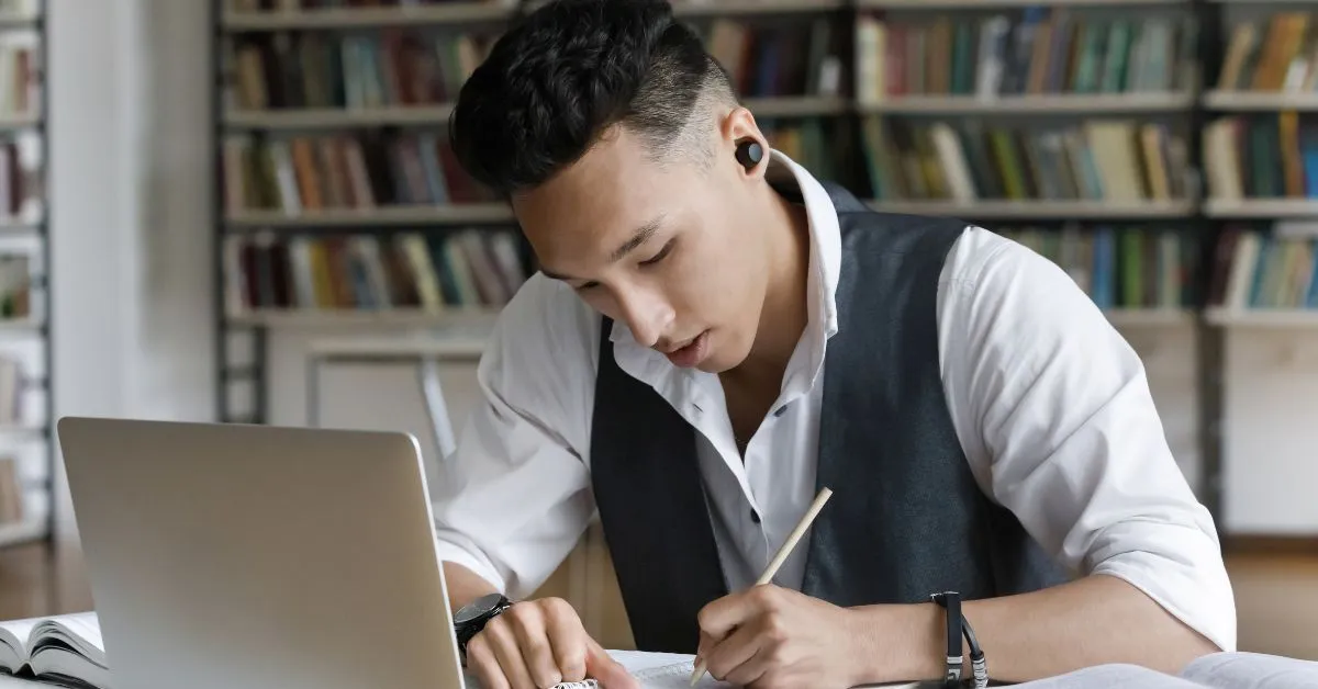 Student wearing noise-cancelling earbuds to focus on studies